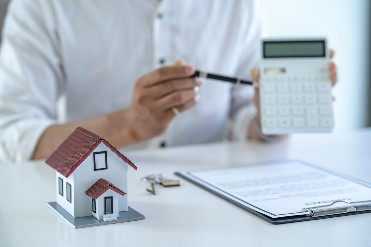 House Deposit Brisbane - a calculator, pen and house model on a desk for saving a house deposit